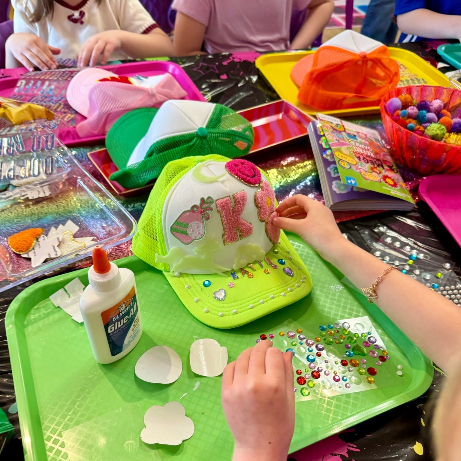 Children engaged in craft activities with decorative hats and materials on a table.