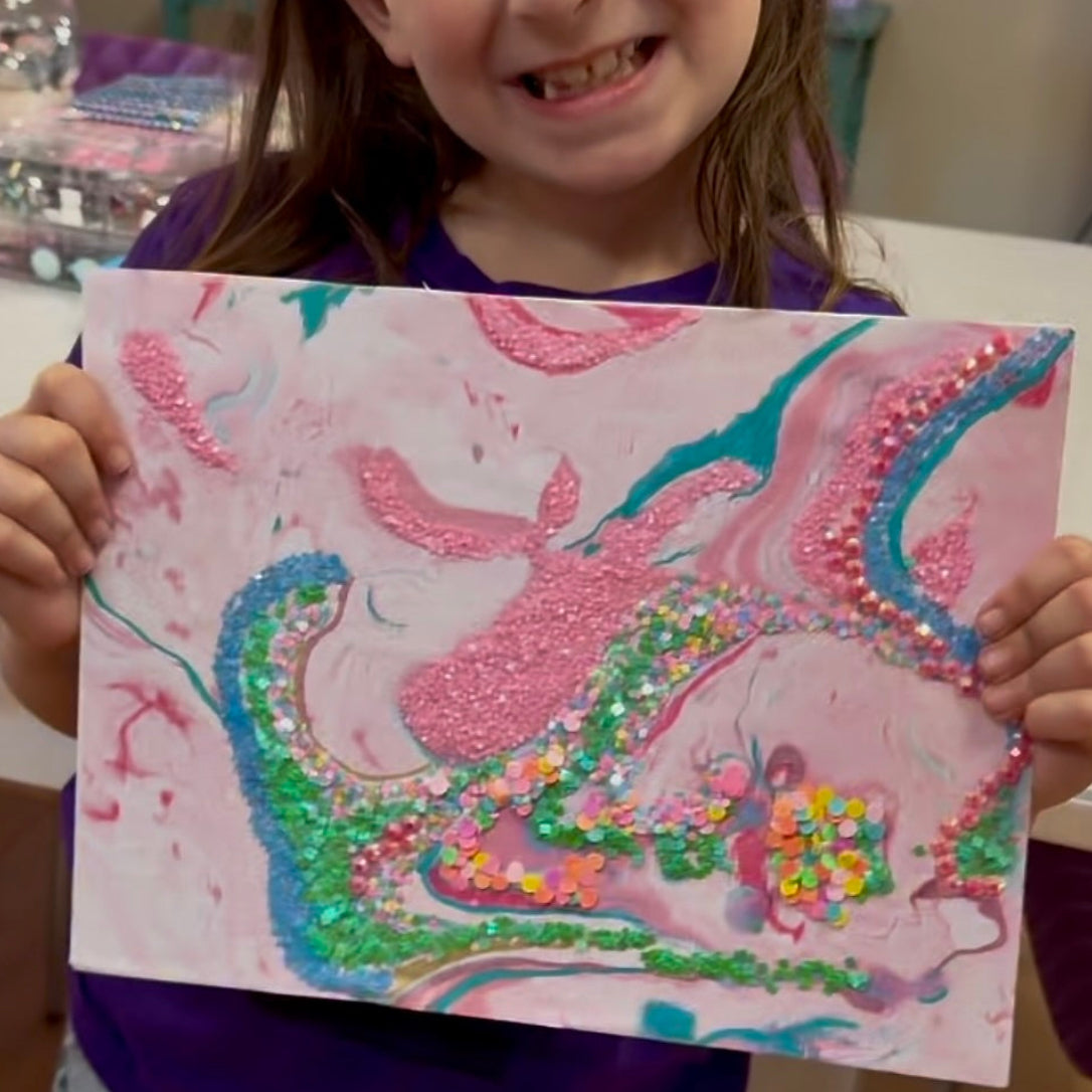 Young girl holding up a colorful drawing of a mermaid and castle.