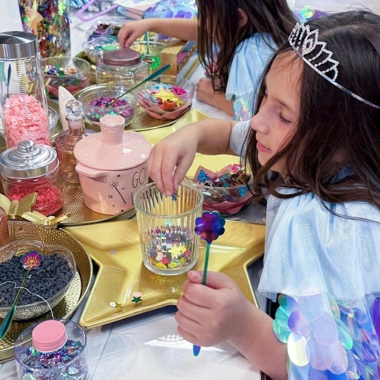 Children playing with decorative items at a table, including a child wearing a tiara.